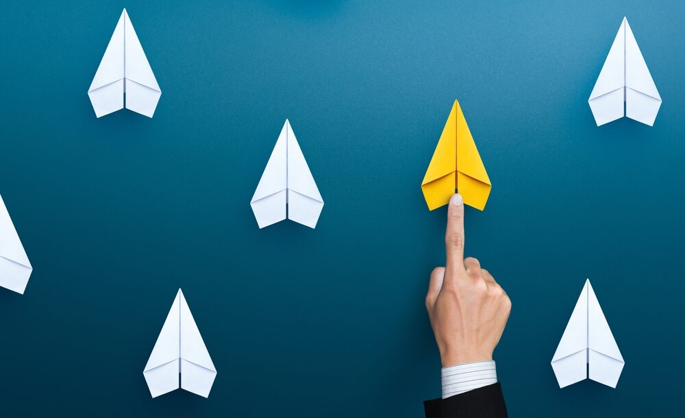 折り紙の船とその中の一つを指さしている手