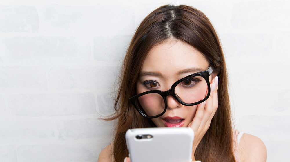 携帯を見てびっくりしている女性